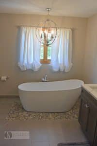 bath design with decorative light fixture over the tub